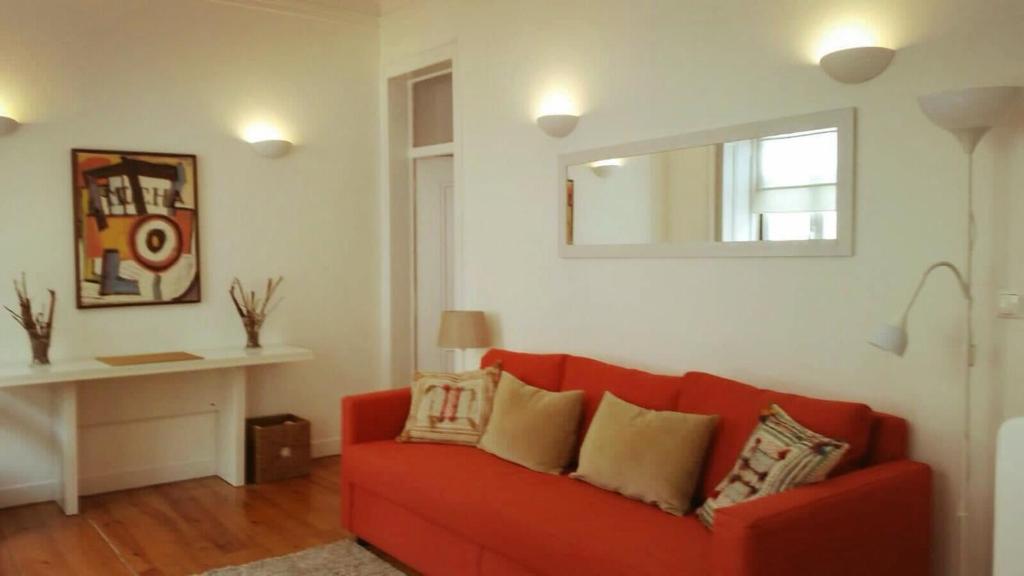 uma sala de estar com um sofá vermelho e um espelho em Lovely Apartment near Belém em Lisboa