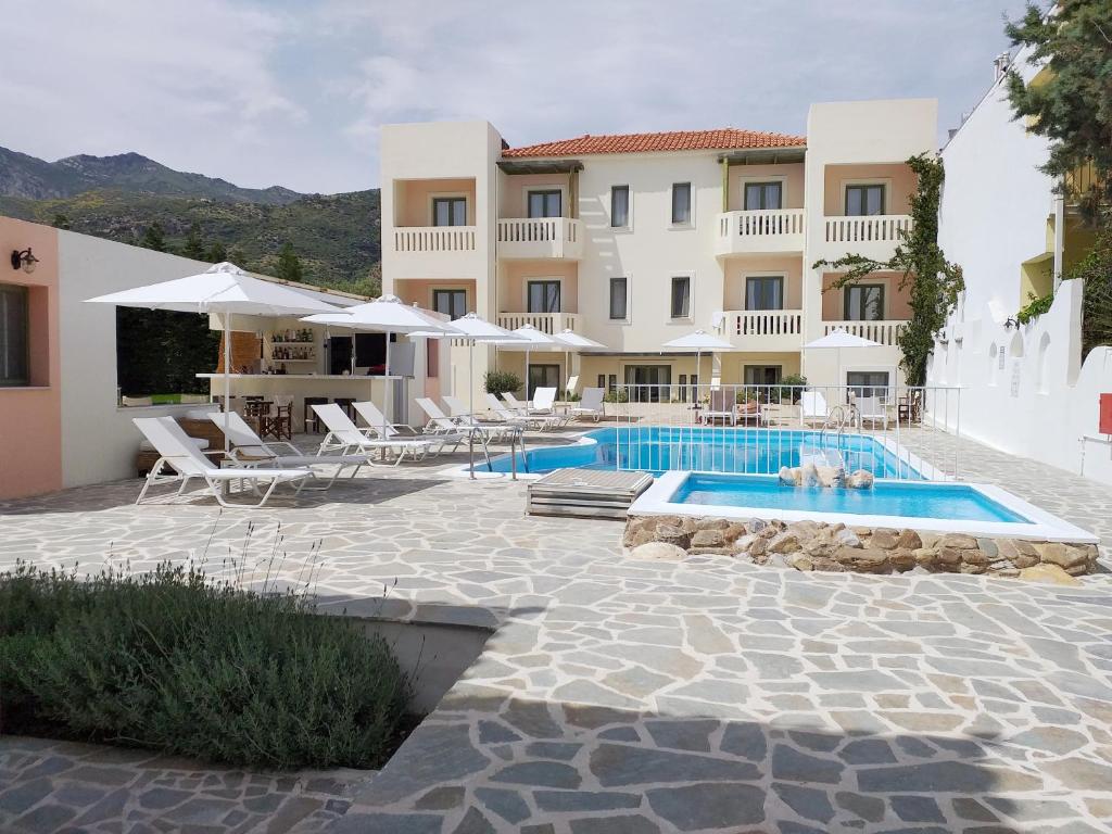 een resort met een zwembad en een gebouw bij Aphrodite Samos Suites in Marathokampos