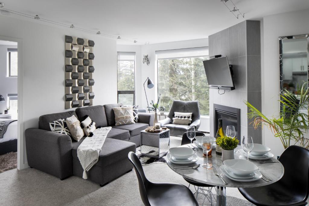 un soggiorno con divano, tavolo e sedie di The Modern Whistler Apartment - Ski-in ski-out a Whistler