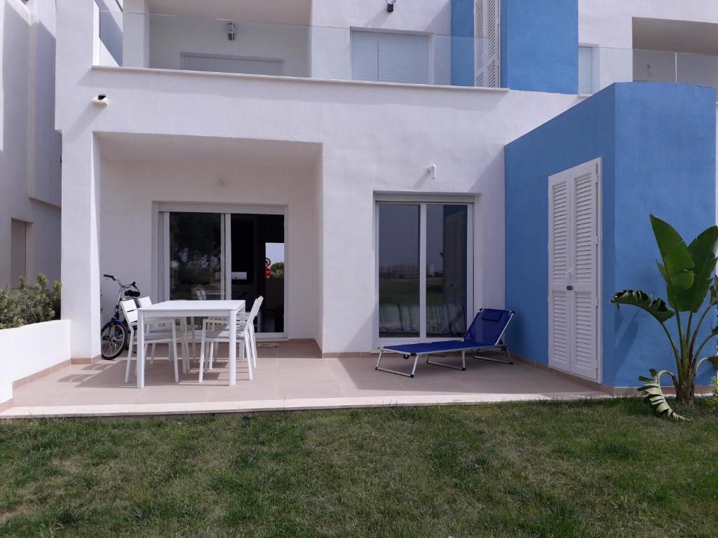 羅爾丹的住宿－Las Terrazas Golf Resort Rental，白色和蓝色的房子,配有桌子和椅子