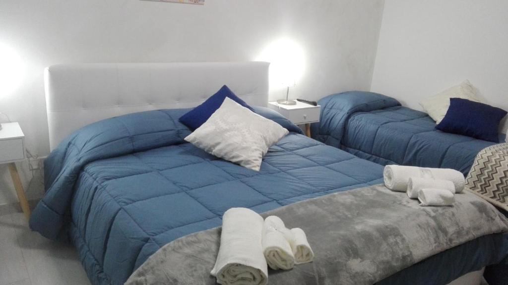 - une chambre avec 2 lits avec des draps bleus et des serviettes dans l'établissement Sweety House, à San Giovanni Gemini