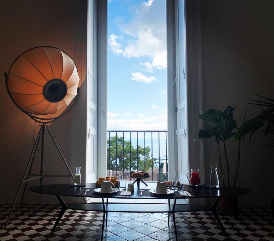 ein Wohnzimmer mit einem Tisch und einem großen Fenster in der Unterkunft PrimoPianoPosillipo in Neapel
