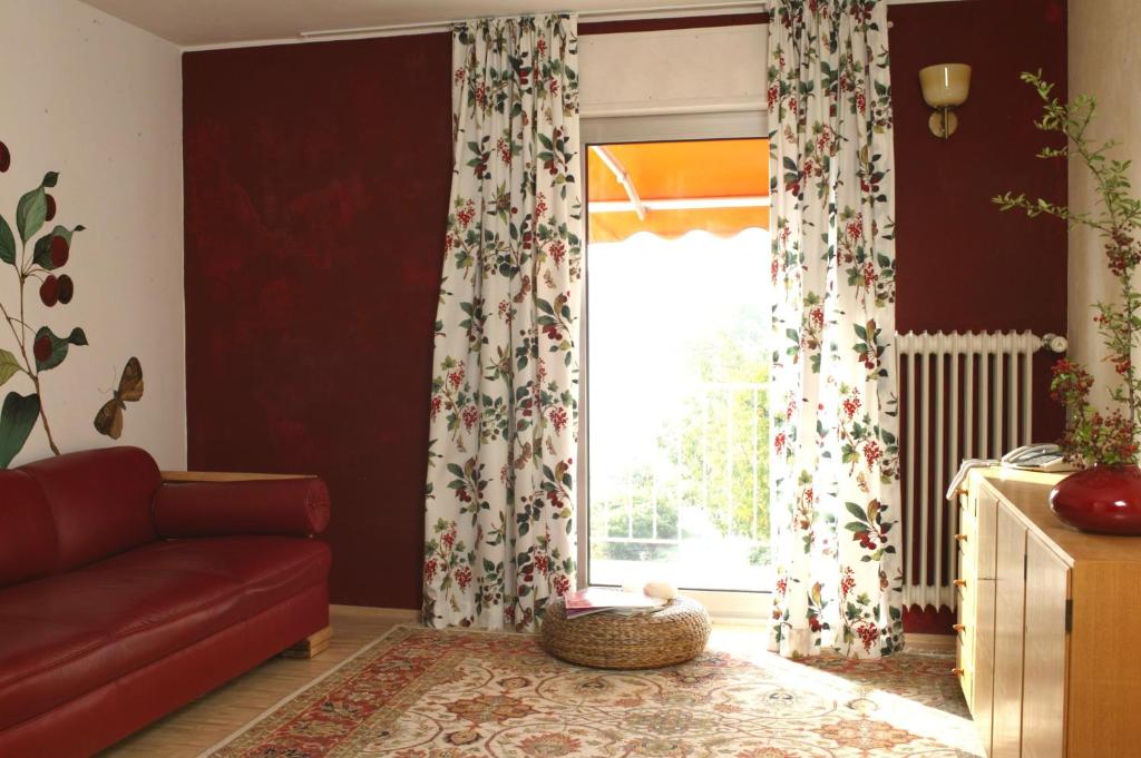 a living room with a red couch and a window at Landhotel Pension Haus Sonneck in Manderscheid