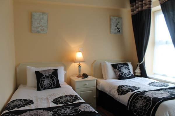 a bedroom with two beds and a window with a lamp at No 1 Leitrim Road in Carrick on Shannon