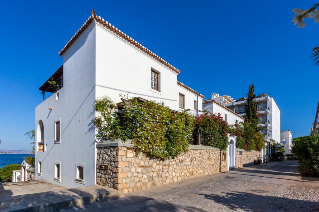 a white building with plants on a stone wall at Villa Ponente in Spetses