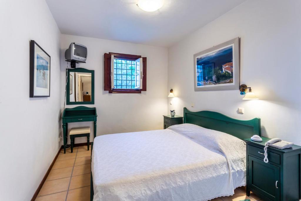 a bedroom with a green bed and a mirror at Villa Ponente in Spetses