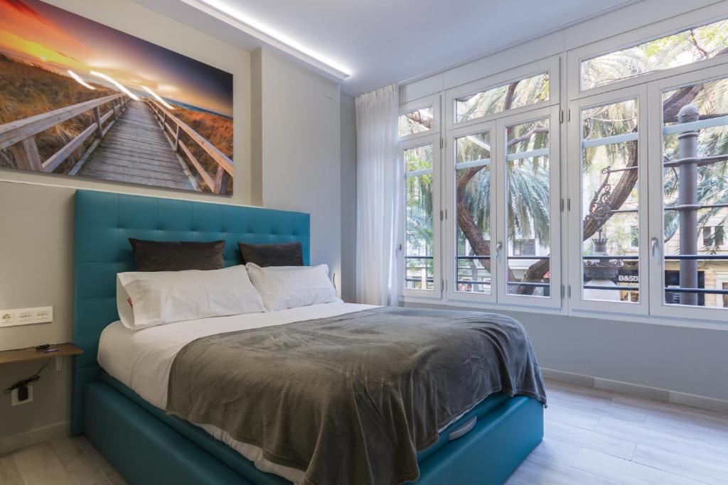 a bedroom with a blue bed with a painting on the wall at A Casa Martínez B&B in Valencia