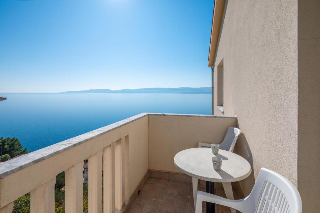 a balcony with a table and chairs and a view of the water at Apartments & Restaurant Galeb in Marusici 