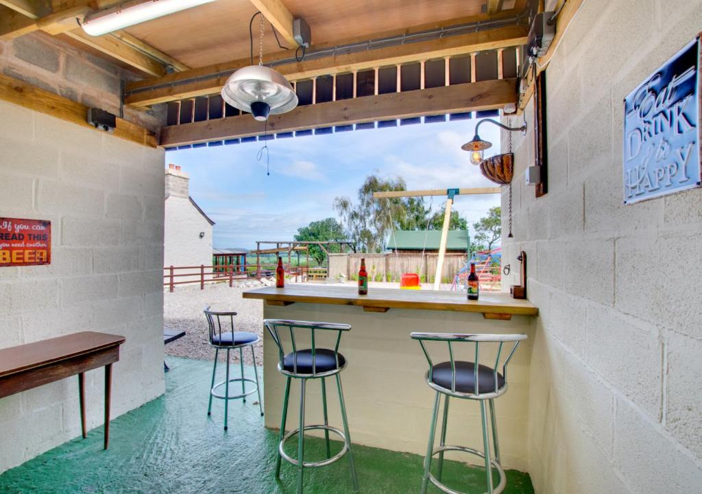 a bar with four stools sitting at a counter at Tan y Garth in Denbigh