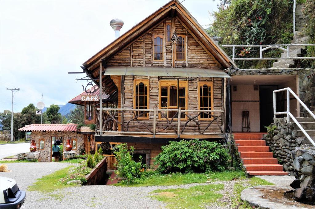 a wooden house with stairs in front of it at Hostería Cabañas del Pescador in Cajas