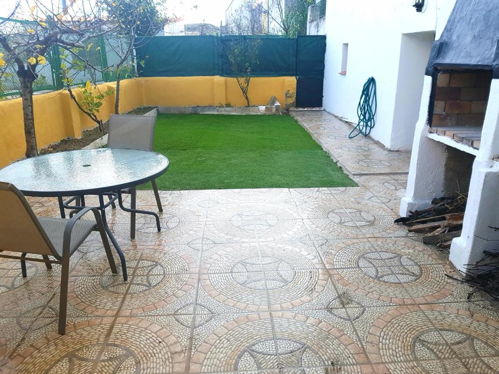 un patio con mesa y césped verde en Casa con jacuzzi la olivera, en Chert