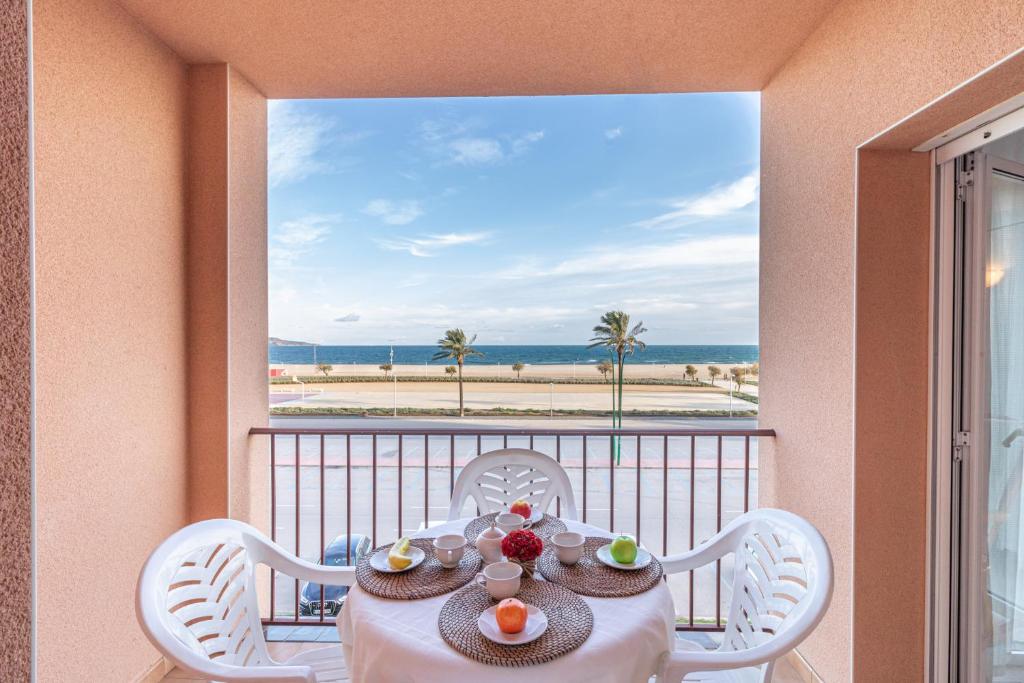 een tafel en stoelen op een balkon met uitzicht op het strand bij Empurialola -Apartamento en primera linea de ma vistas al mar -164 in Empuriabrava