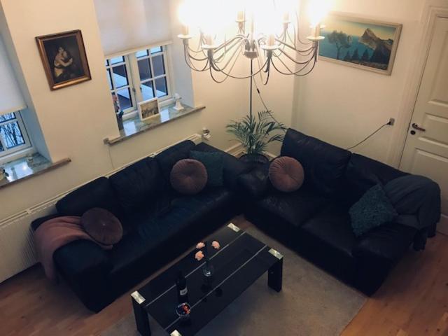 a living room with a black couch and a table at Centralt i Gentofte i 2 plan, ved S-Tog og busser in Gentofte
