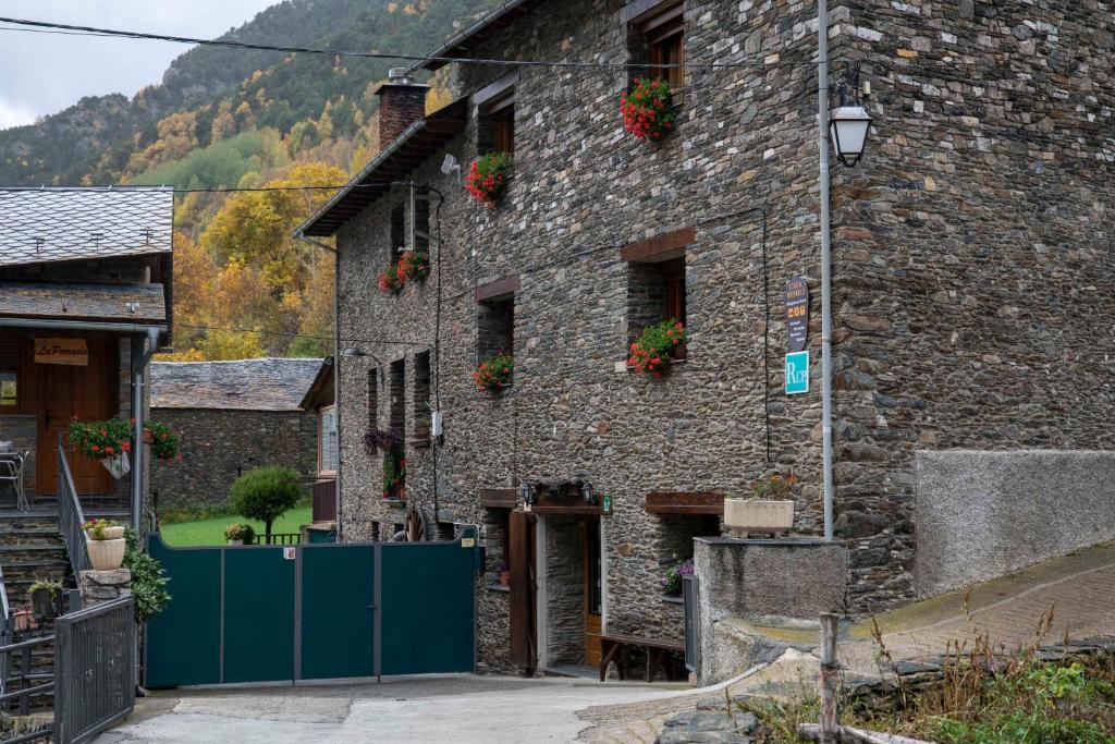 een oud stenen gebouw met bloemen op de ramen bij Casa Rural Besolí in Areu