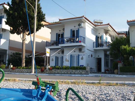 una casa blanca con un edificio en el fondo en Oceanis Hotel, en Tyros