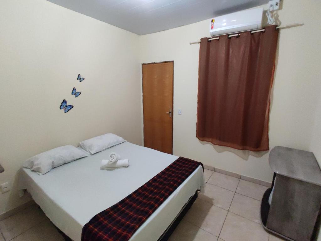um quarto com uma cama, uma cadeira e uma janela em Pousada do Professor em Pirenópolis