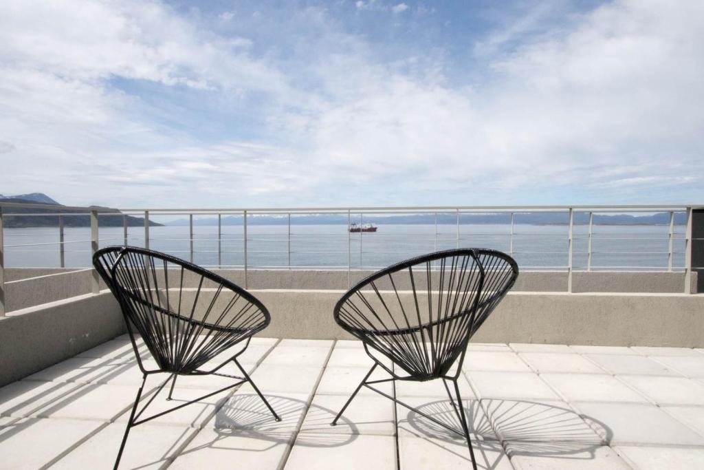 Duas cadeiras numa varanda com vista para o oceano em De la Costa Apartamentos em Ushuaia