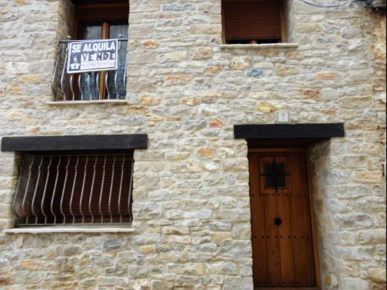 un edificio de ladrillo con una puerta y una señal en él en Apartamentos Ines, en Valdelinares