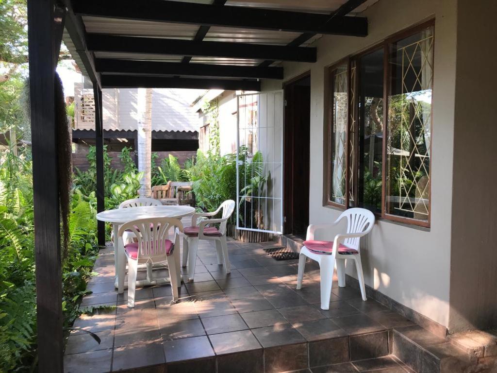 a patio with a table and chairs on a porch at Umlalazi Cottage in Mtunzini