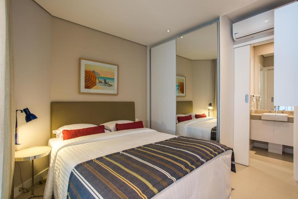 a bedroom with a large bed and a bathroom at Residencial Estanconfor Santos in Santos