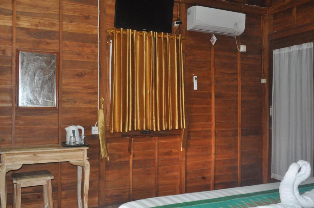 a room with wooden walls and a table and a window at KKorok Hill Cottage in Nusa Penida