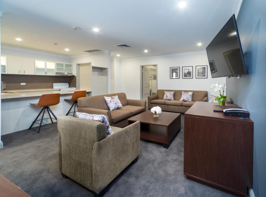 a living room with two couches and a kitchen at Hyde Park Inn in Sydney