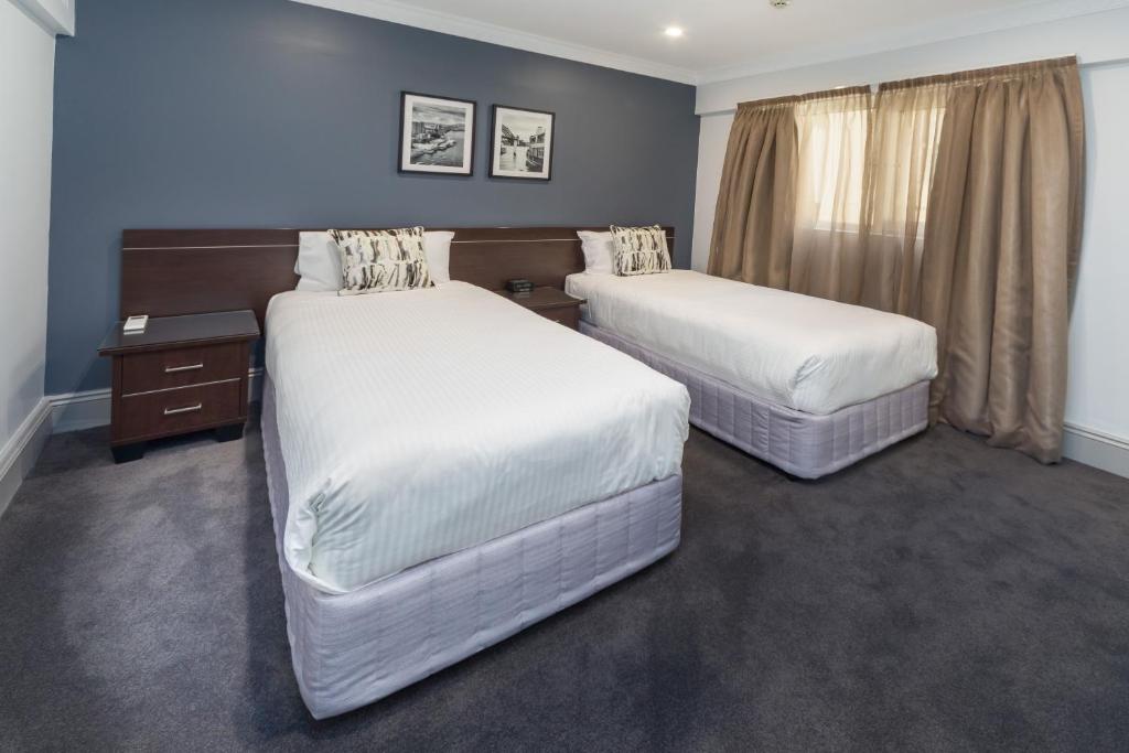 two beds in a room with blue walls at Hyde Park Inn in Sydney