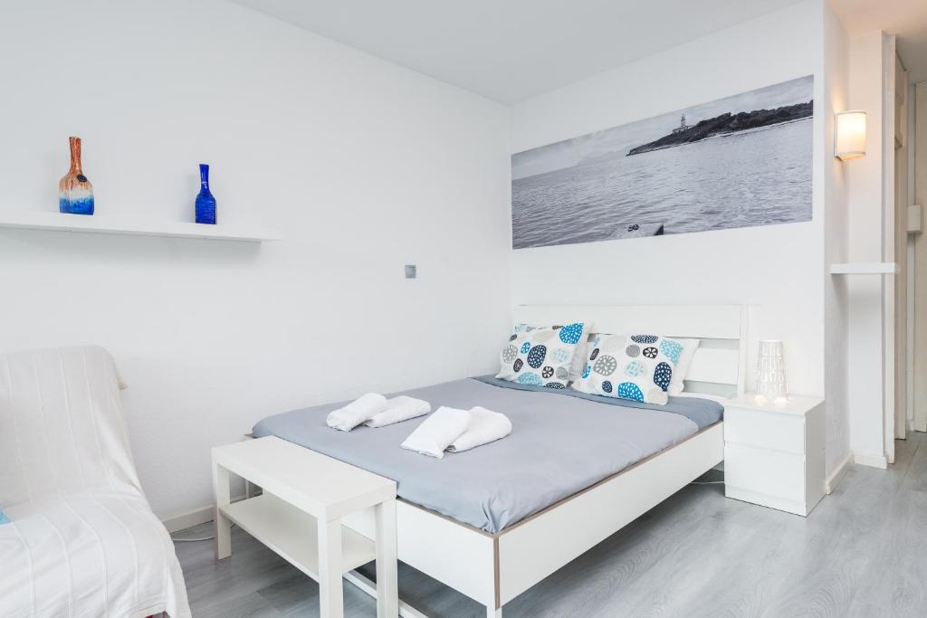 een witte slaapkamer met een bed en een stoel bij Nice Studio in Siesta 2 in Puerto Alcudia 2 in Alcudia