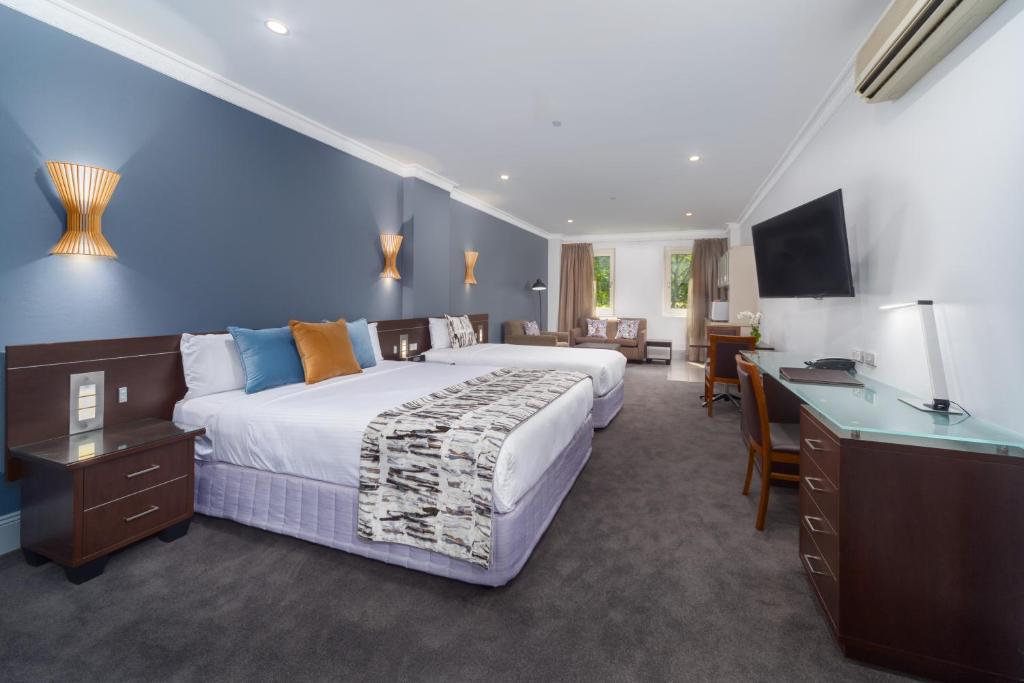 シドニーにあるハイド パーク インの大きなベッドとデスクが備わるホテルルームです。