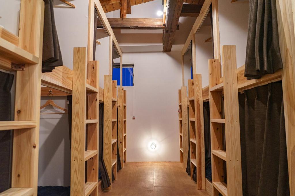 eine Reihe von Etagenbetten aus Holz in einem Zimmer in der Unterkunft ゲストハウス さんかくワサビ in Saiki