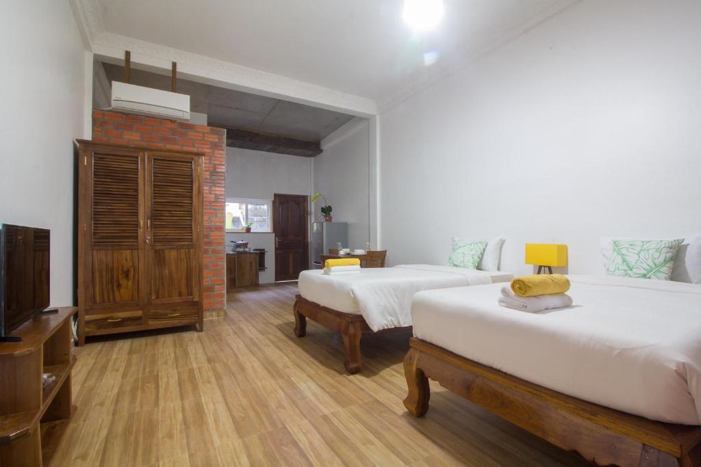 a bedroom with two beds and a television in it at ANGKOR DINO HOME in Siem Reap