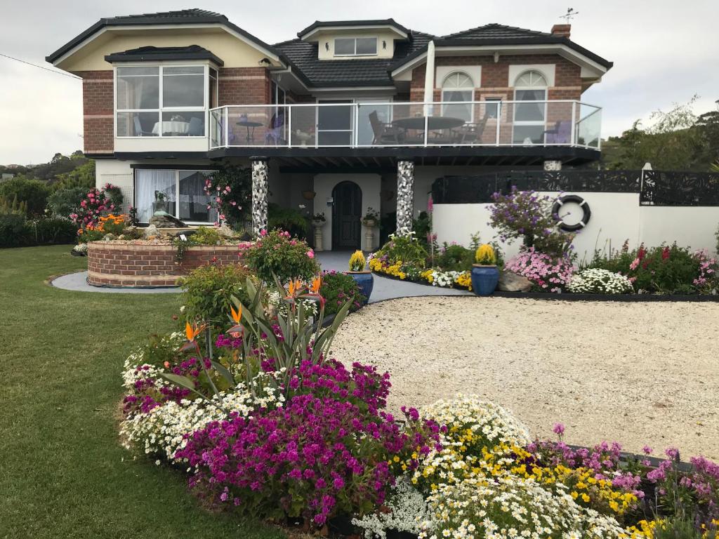 
a house that has a garden with flowers in front of it at Moonlight Bay B&B Guest House in Ulverstone
