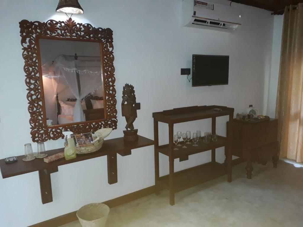 a mirror on a wall with two tables and a television at Selnara Private Luxury Villa and Ayurveda Spa in Bentota