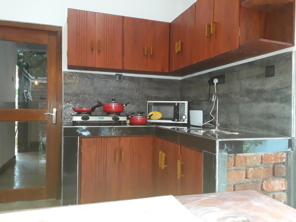 a kitchen with wooden cabinets and a microwave at Selnara Private Luxury Villa and Ayurveda Spa in Bentota