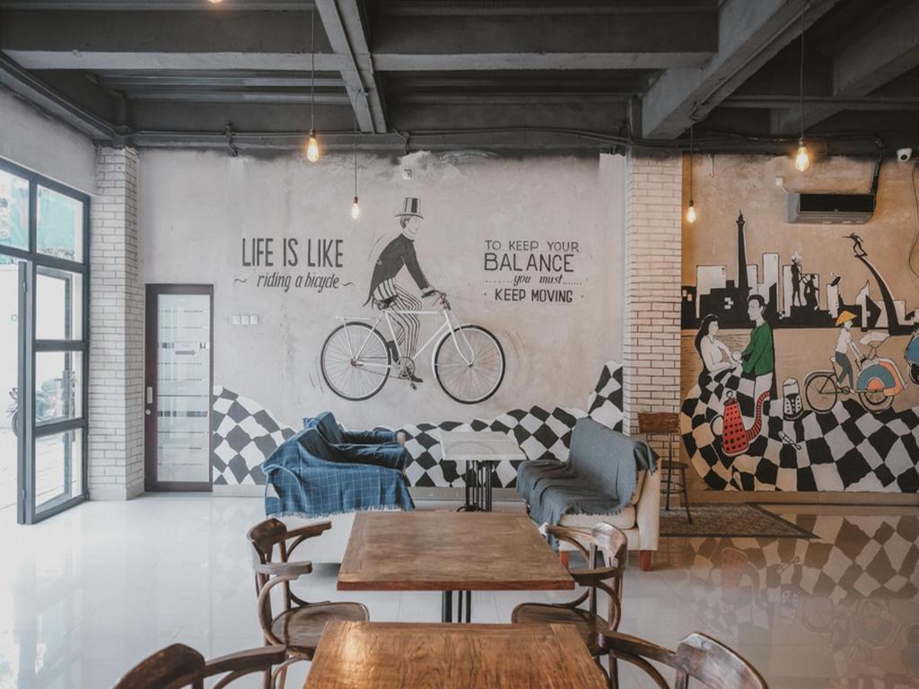un restaurante con mesas y sillas y una pared con pinturas en RedDoorz near Plaza Atrium Senen en Yakarta