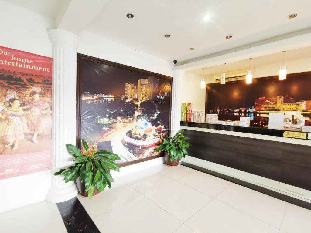 um restaurante com dois vasos de plantas e um grande ecrã em Homestay Kuching Hotel em Kuching