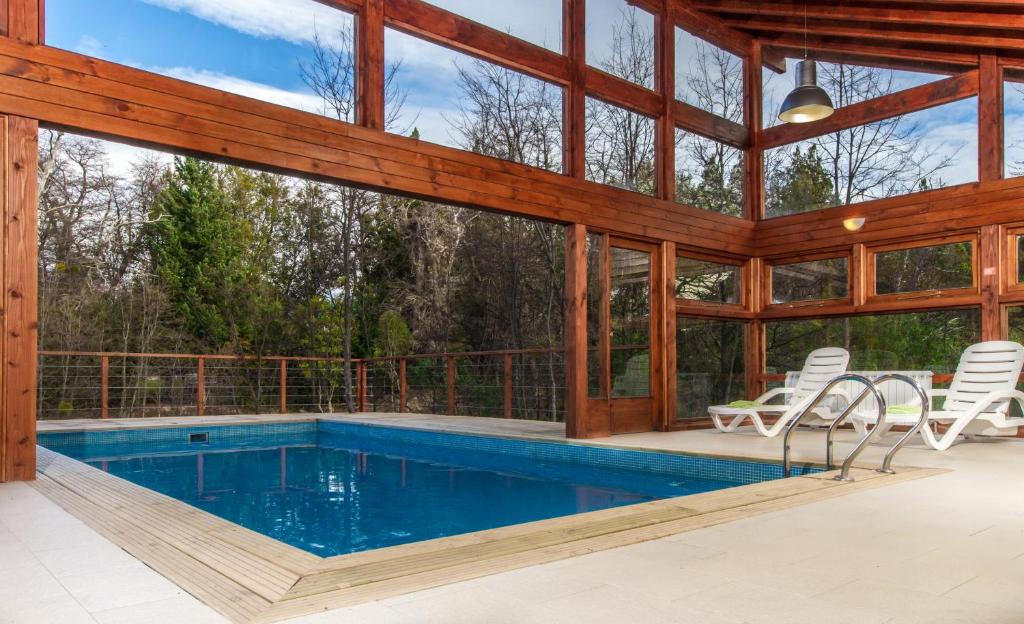 uma piscina interior numa casa com uma parede de vidro em Arbolar em Villa La Angostura