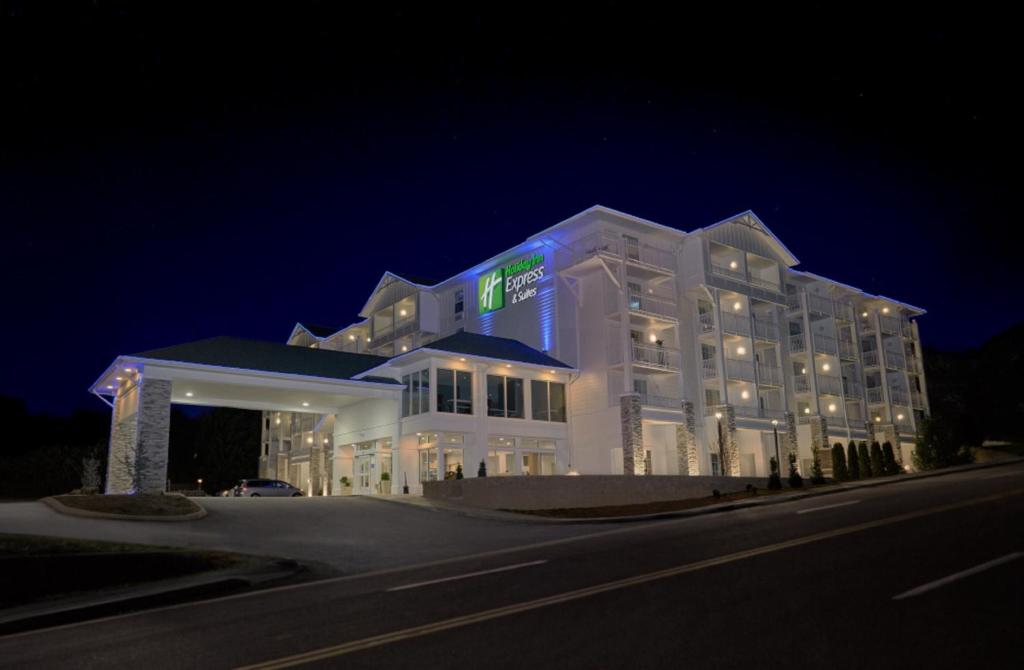 Holiday Inn Express Pigeon Forge – Sevierville, an IHG Hotel في بيدجن فورج: مبنى أبيض كبير مع وجود علامة عليه في الليل