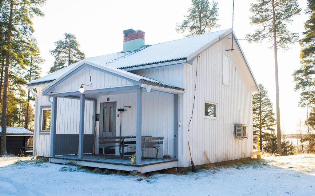 a white building with a porch in the snow at Holmens Boende och Event in Luleå