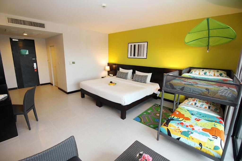 a room with two beds and a desk and a table at Simplitel in Karon Beach