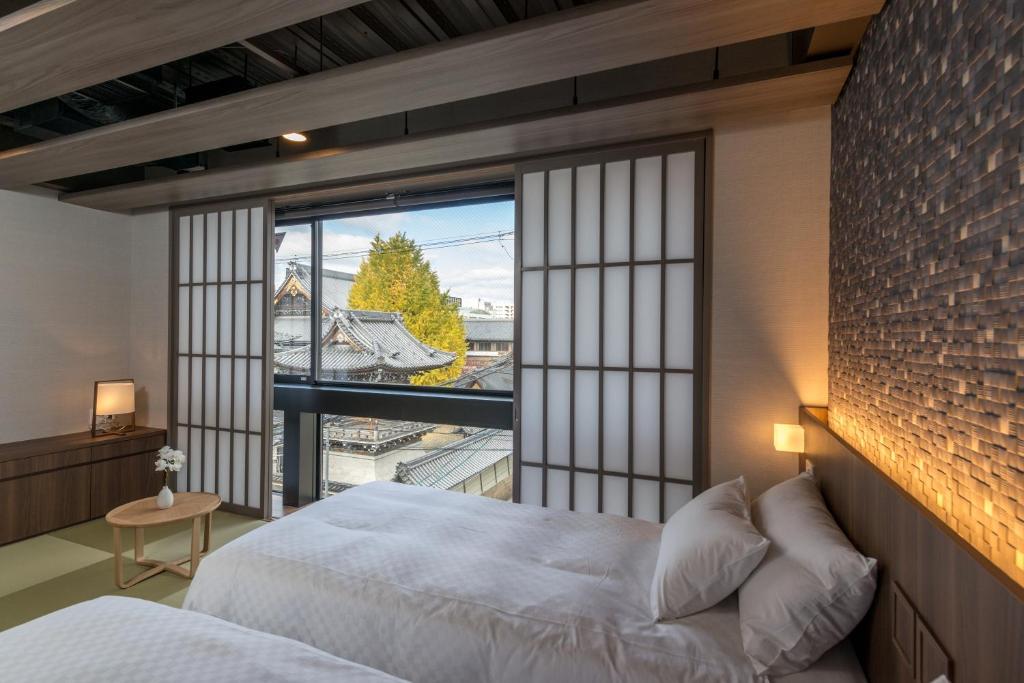 a bedroom with a bed and a large window at 谷町君・ホテルひとめぼれ 京都四条烏丸 in Kyoto