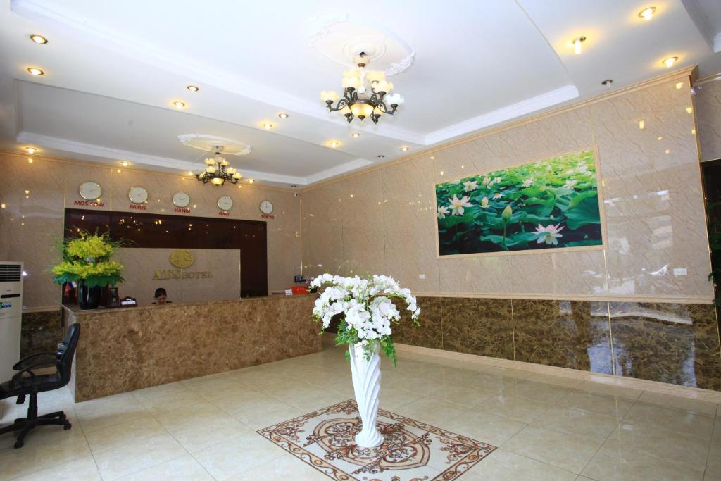 um lobby com um vaso de flores sobre uma mesa em ATS Hotel em Hanói