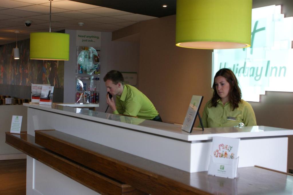 dos personas sentadas en un mostrador en un restaurante en Holiday Inn Huntingdon Racecourse, an IHG Hotel, en Huntingdon