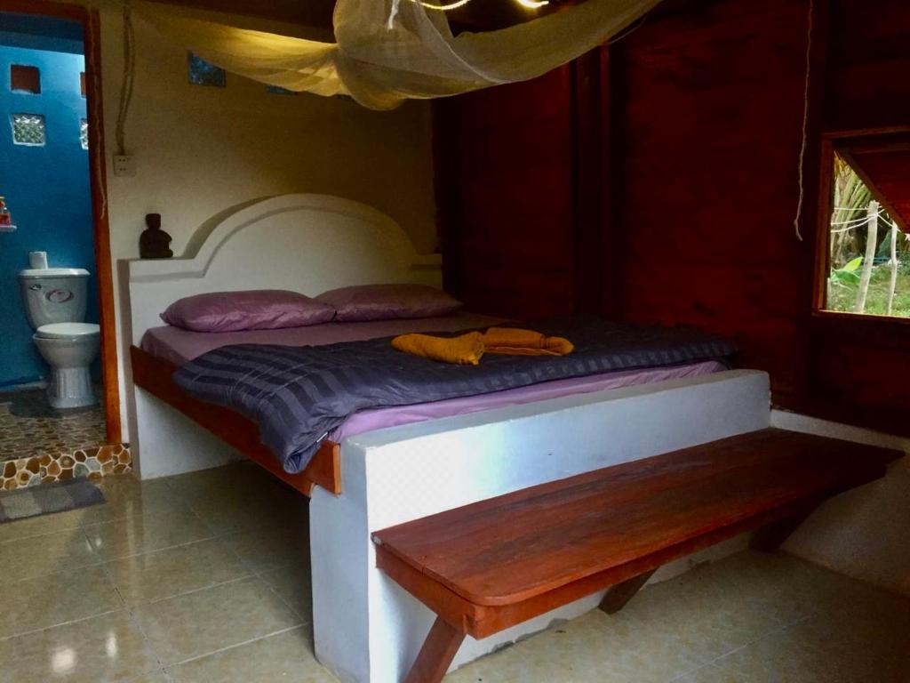 a small bed in a room with a bench at Lazy Bones in Koh Rong Sanloem