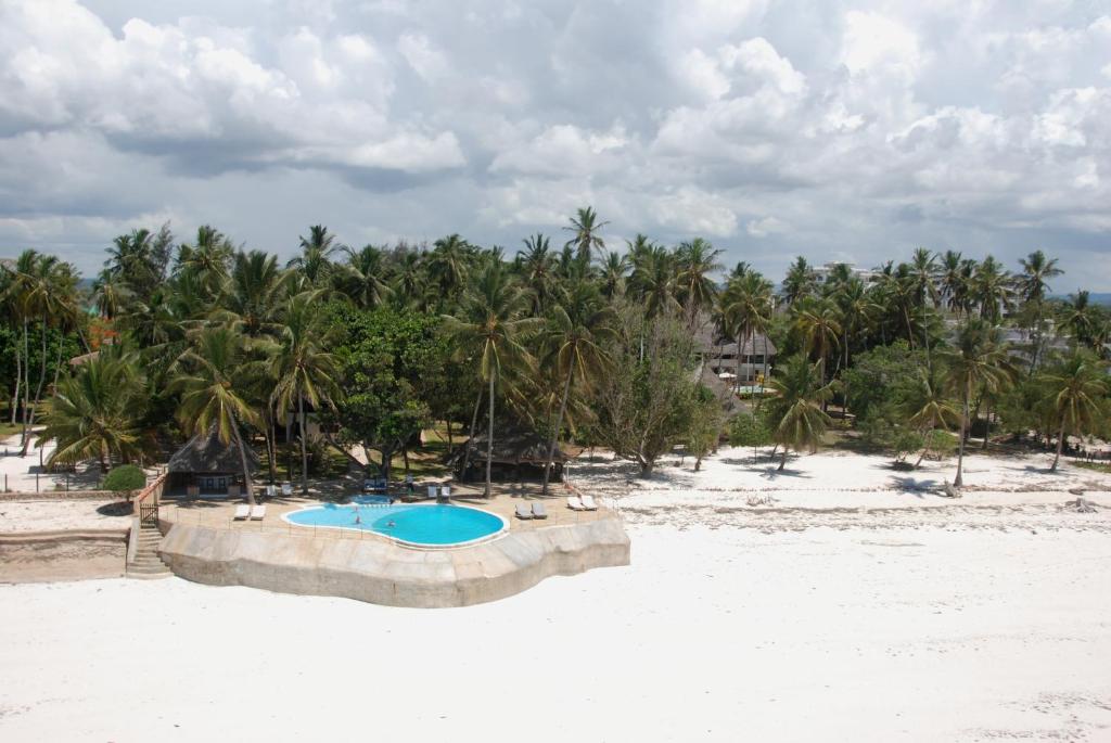 una piscina su una spiaggia con palme di Kusini Beach Cottages a Diani Beach