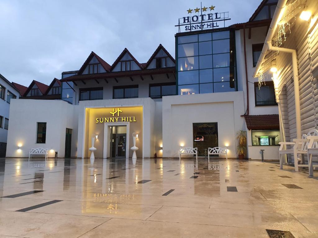 un gran edificio blanco con un patio con mesas y sillas en Hotel Sunny Hill, en Cluj-Napoca