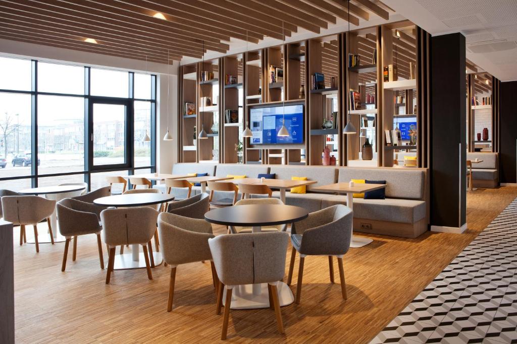 een restaurant met tafels en stoelen en een tv bij Holiday Inn Express Oberhausen by IHG in Oberhausen