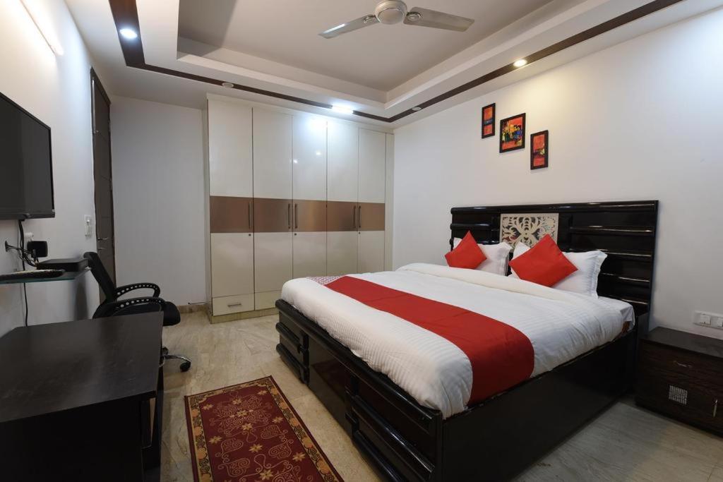 新德里的住宿－Golden Bed and Breakfast- High Quality Rooms in South Ex-1 D Block，一间卧室配有一张带红色枕头的床和一张书桌