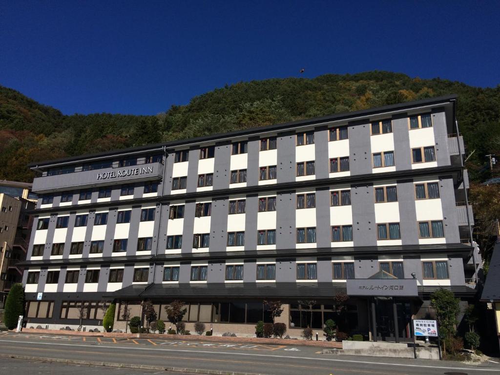 a large white building on the side of a street at Hotel Route-Inn Kawaguchiko in Fujikawaguchiko