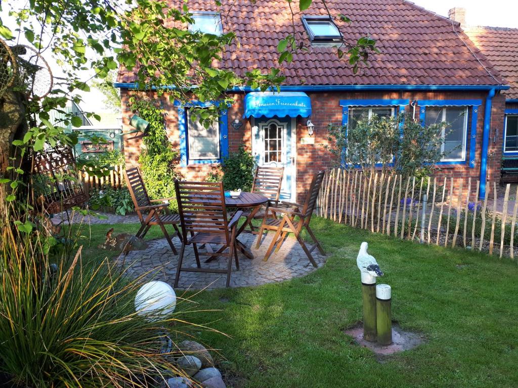 een achtertuin met een tafel en stoelen en een hek bij Villa Friesenkät in Wangerland